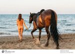 Schöne nackte Frau zu Fuß am Strand mit ihrem Pferd bei Sonn